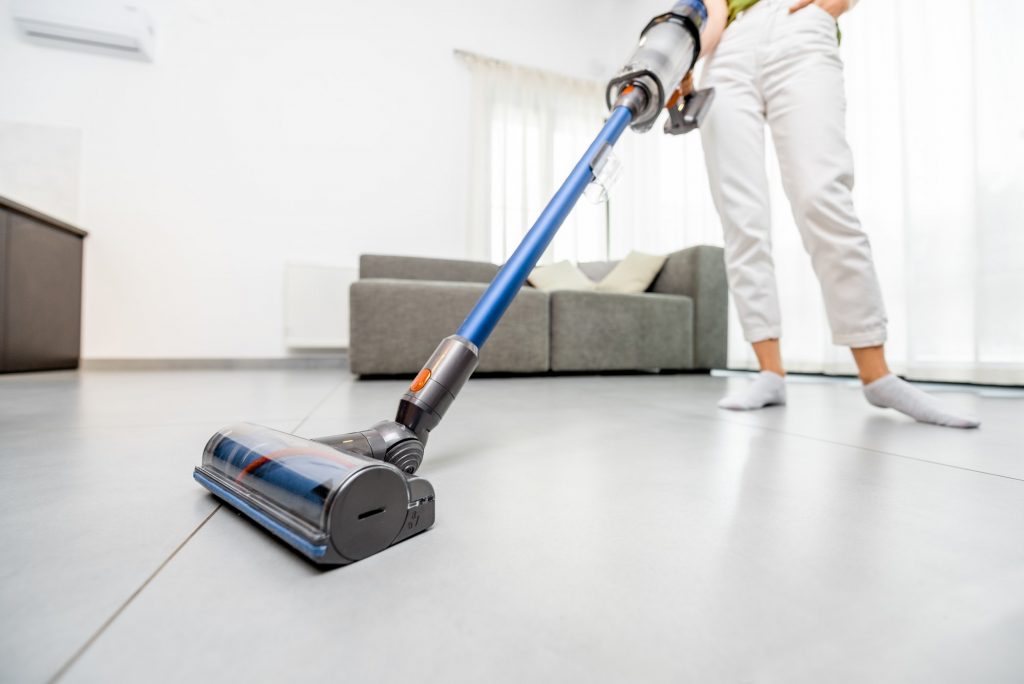 Woman cleaning floor with cordless vacuum cleaner